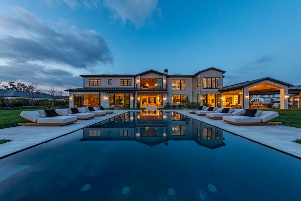 Completed luxury estate at twilight with infinity pool and modern farmhouse architecture